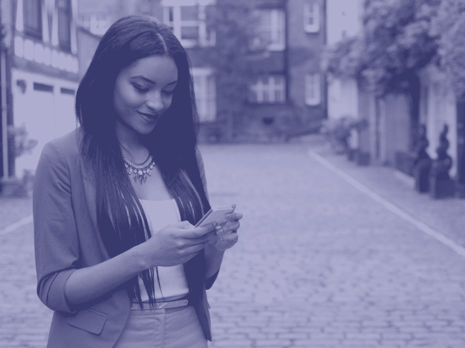 Woman smiling down at phone in hands on street