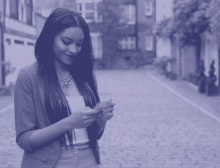 Woman smiling down at phone in hands on street