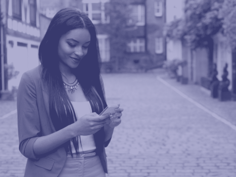 Woman smiling down at phone in hands on street