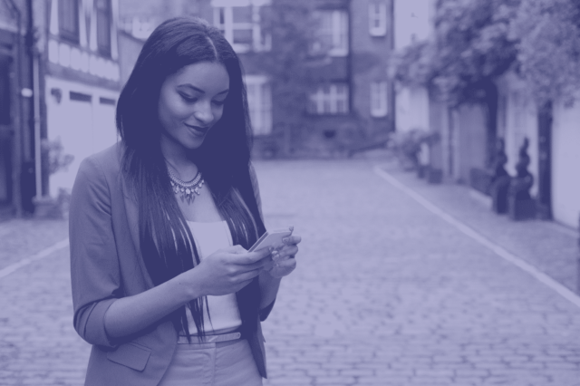 Woman smiling down at phone in hands on street