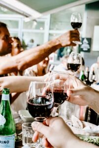 many hands clinking wine glasses together